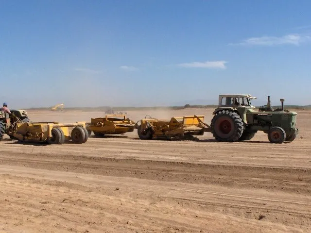 Tractor tirando palas de arrastre sobre un terreno en nivelación